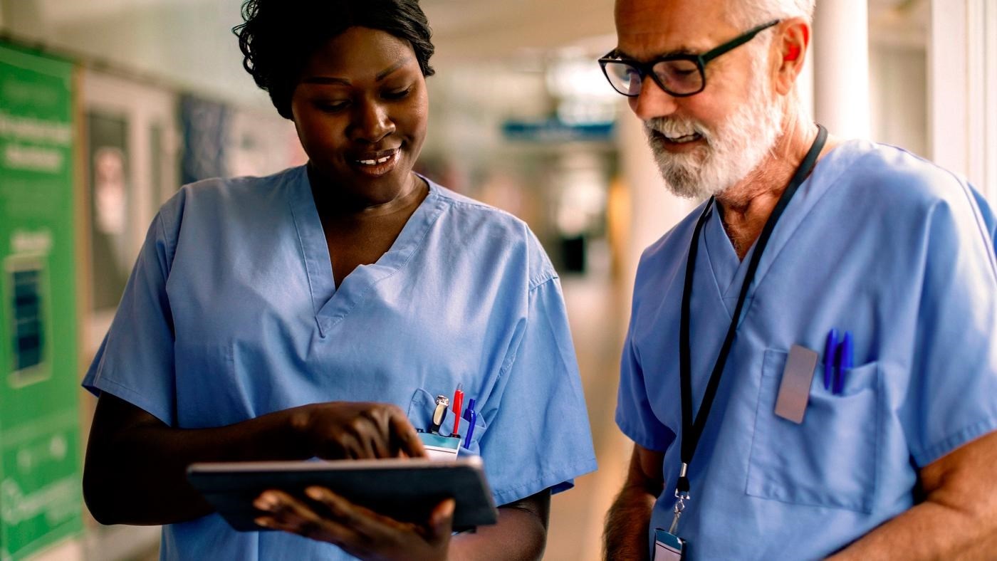 Smiling nurse showing tablet to colleague