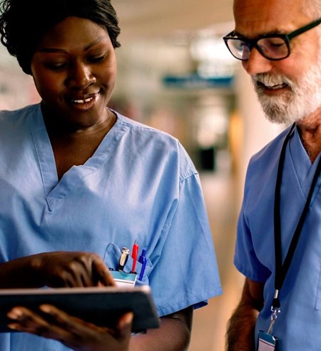 Smiling nurse showing tablet to colleague