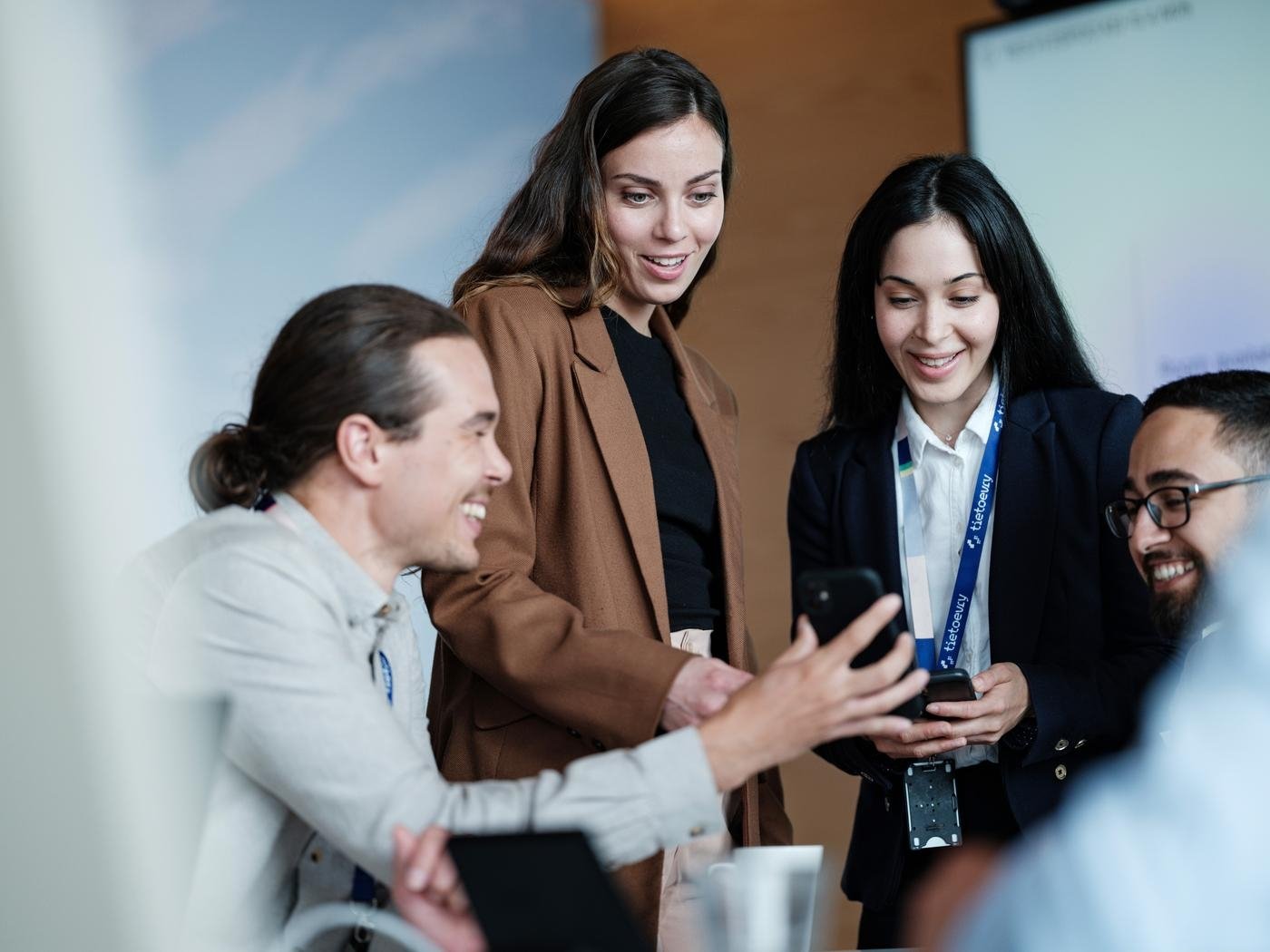 Tietoevry employees with badges meeting in the office looking at a phone's screen