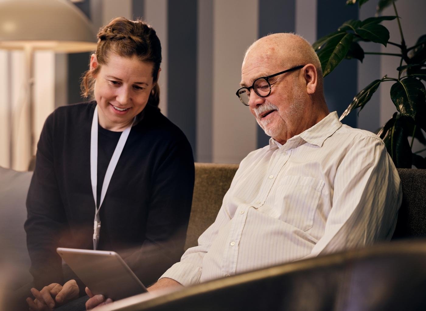 Social worker helping an elderly man with technology