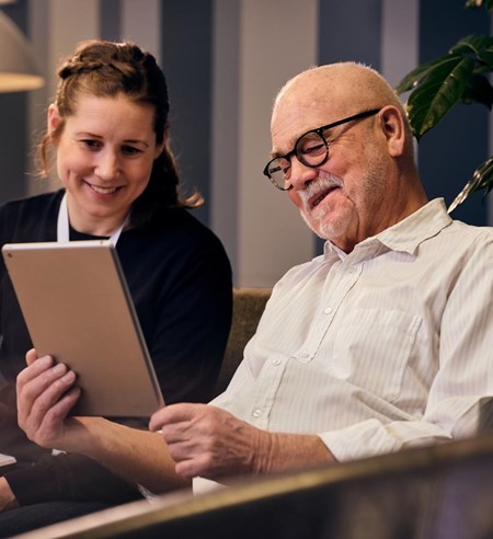Social worker and an elderly man looking at tablet
