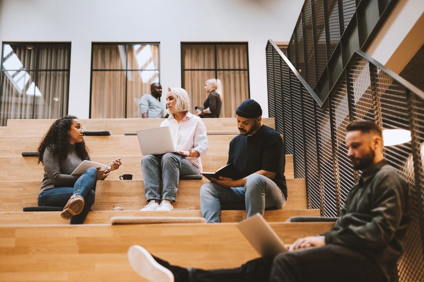 students sitting on stairs with notebooks and laptops