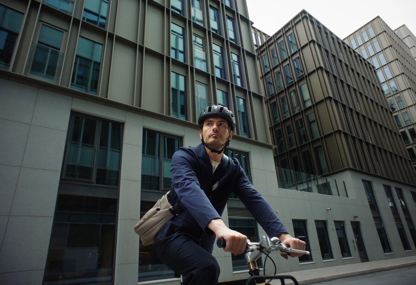 A young man on a bike with a messenger bag in a financial district