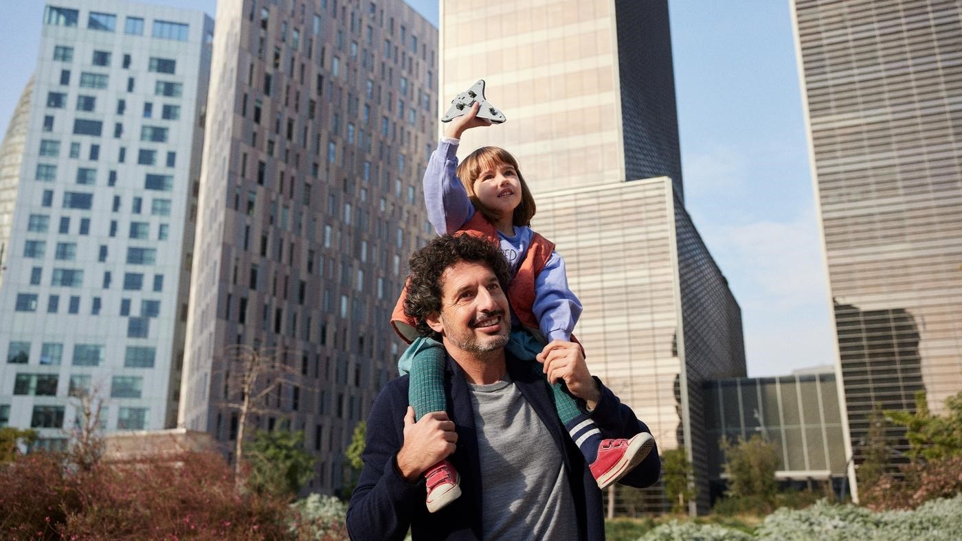 Dad carries his daughter on his sholders in the city environment