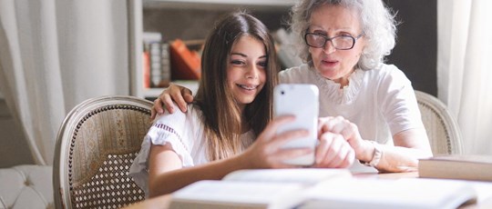 Studying girl showing grandma smartphone