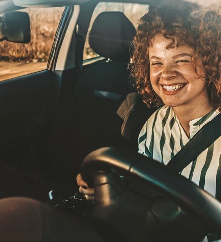 Young woman driving a car, smiling