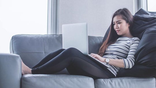 Woman sitting on a sofa, working with her laptop