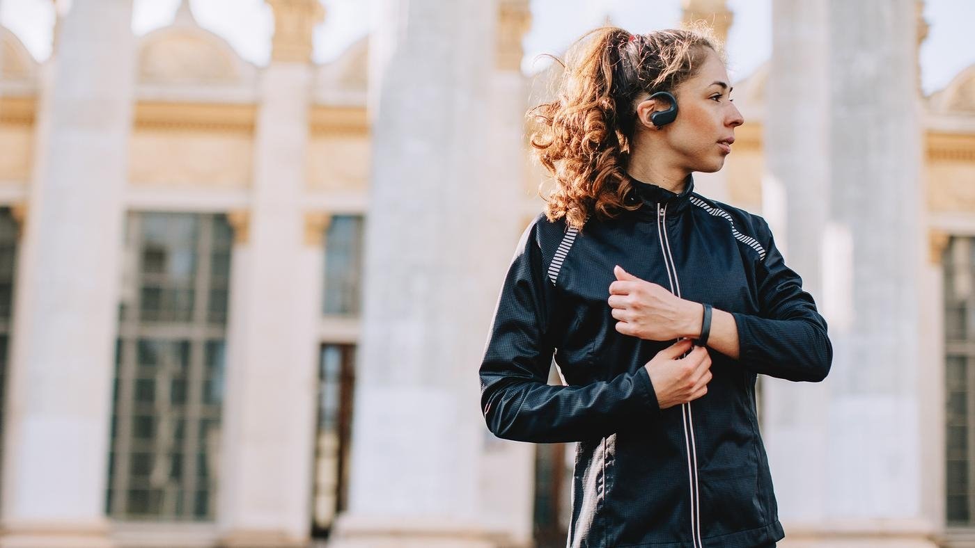 Young female athlete listening to music outdoors