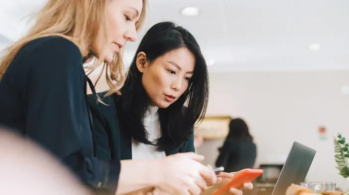 Colleagues use mobile phones during conferences in offices